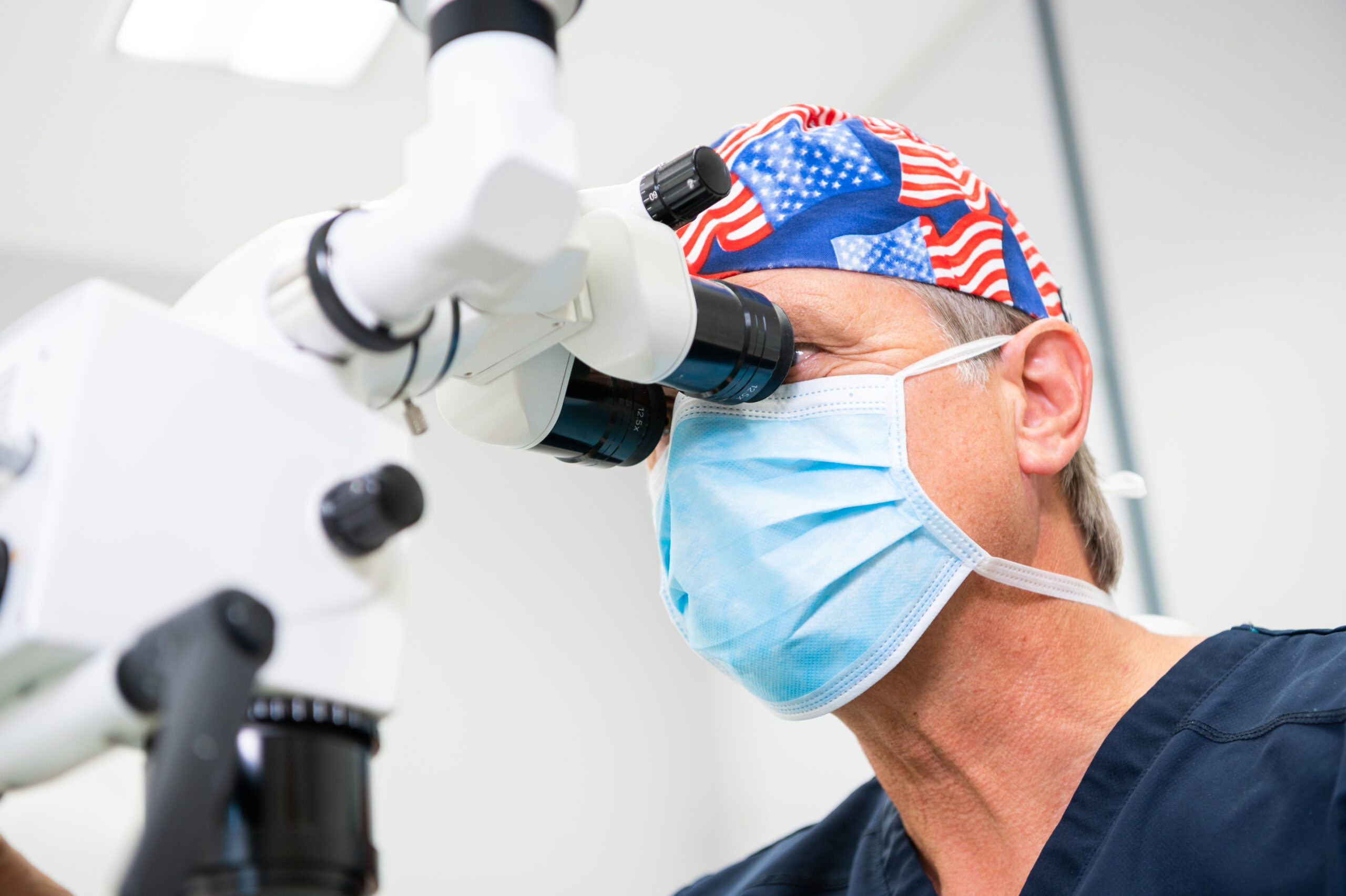 Der Arzt Dr. Strese schaut durch eine Binokularische Lupe